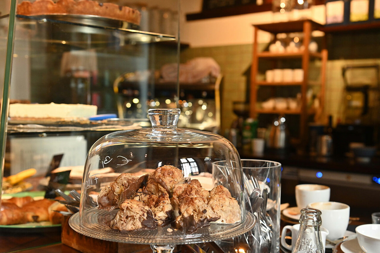 Blick auf eine Cafétheke. Unter einer Glasglocke liegen Croissants mit Schokospitze. Im Hintergrund ist unscharf eine Art Küche zu erkennen
