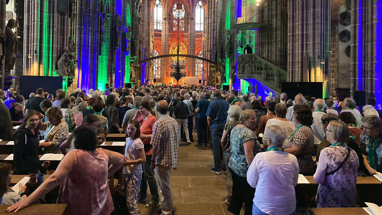 Hunderte Menschen in der bunt erleuchteten Sankt Lorenz Kirche in Nürnberg 2023