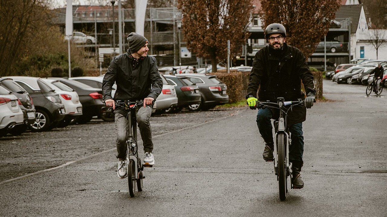 Zwei Männer auf Elektrofahrrädern auf einem Parkplatz