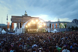 angeleuchtete Bühne vor dem Brandenburger Tor, davor eine große Menge Menschen