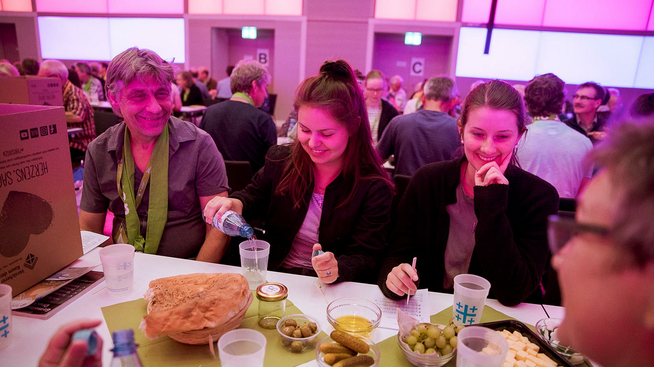 Personen sitzen gemeinsam an einer gemeinsamen Tafel