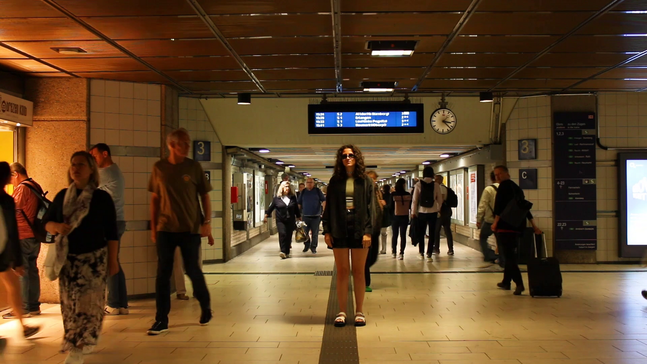 Frau steht in der B-Ebene der U-Bahn, während Menschen um sie herum laufen