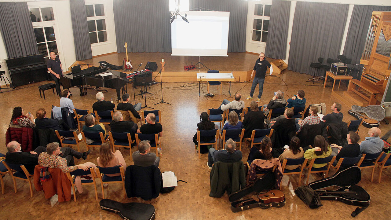 Ein Saal mit Instrumenten und Sitzreihen in denen die Teilnehmenden der Liederwerkstatt sitzen