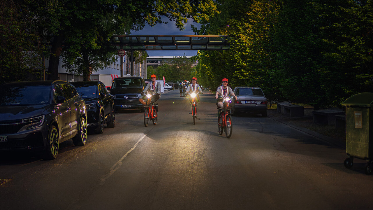 Symbolbild: Drei ehrenamtliche Helfer mit Fahrrädern und eingeschalteter Beleuchtung bei einer abendlichen Fahrt während des Kirchentages. Steht stellvertretend für die erfolgreiche Fahrrad-Challenge 'Kirchentag mit Rad', bei der Teilnehmende über 14.000 Kilometer für Nachhaltigkeit und Gemeinschaft erradelten.