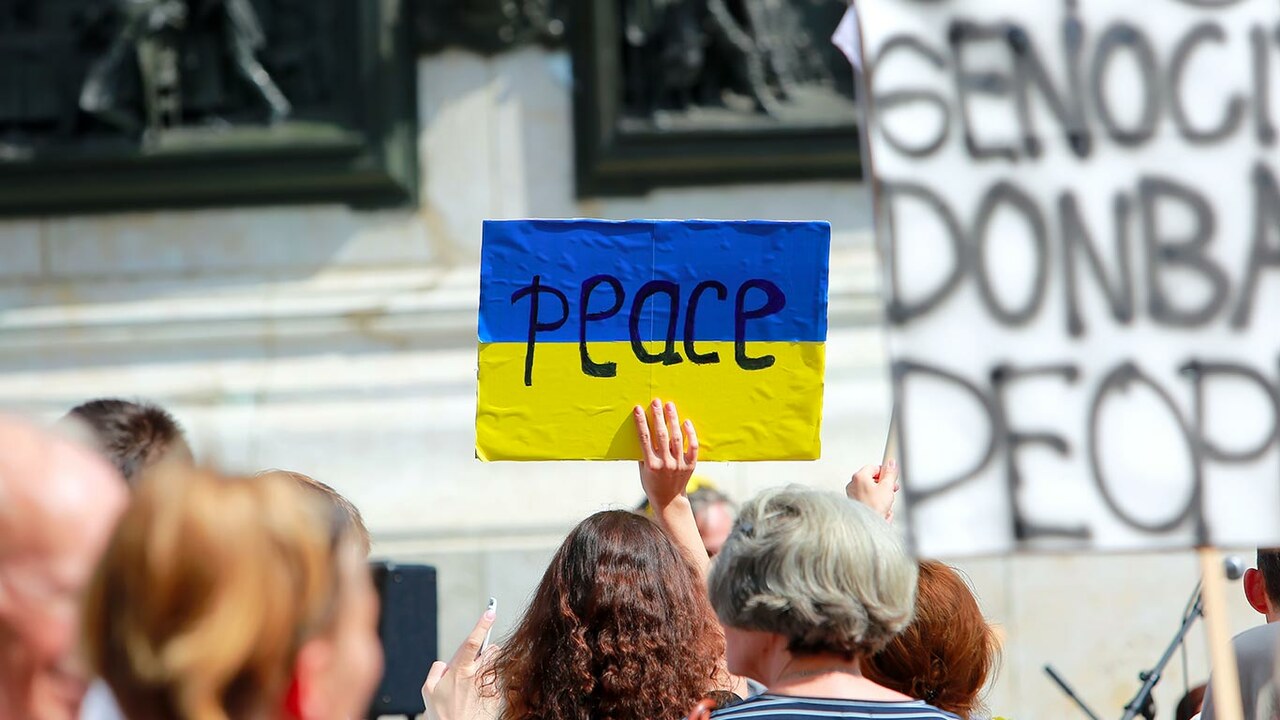 Demonstration für Frieden. Schild mit Ukrainischer Flagge und "peace".