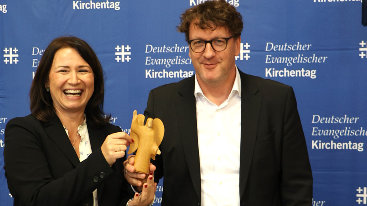 Übergabe: Anja Siegesmund und Torsten Zugehör bei der Präsidialversammlung. Es wird symbolisch ein Engel überreicht. (Foto: Kirchentag/ M. Zeißig)