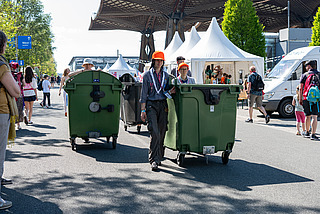 Helfende schieben Mülltonnen über das Veranstaltungsgelände