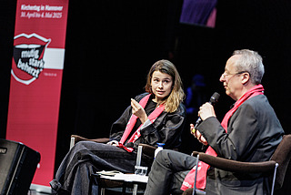 Zwei Personen sprechen auf der Bühne miteinander bei einer Dialogbibelarbeit
