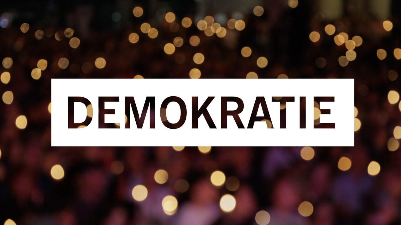 Schriftzug "Demokratie" im Hintergrund verschwommen der Nachtsegen am Opernplatz