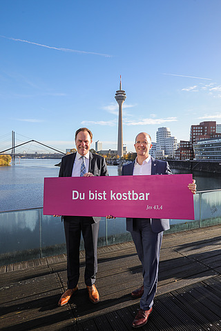 Oberbürgermeister Stephan Keller und Präses Thorsten Latzel mit Losung des Kirchentages 2027 in Düsseldorf