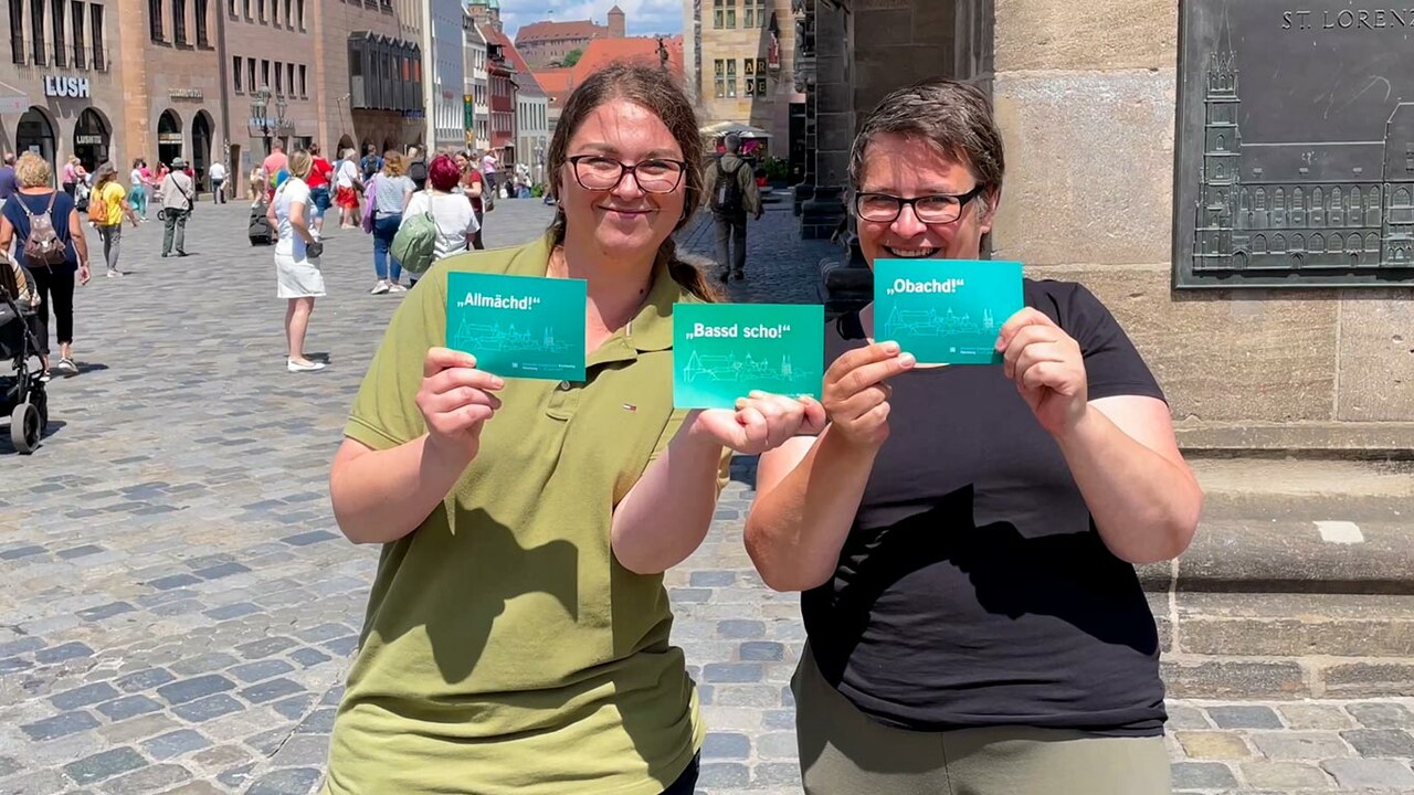 Zwei Frauen mit Postkarten vom Kirchentag in der Hand in der Nürnberger Altstadt.
