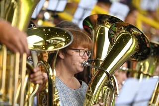 Drei große goldene Tubas, mittig im Bild eine Bläserin mit Brille und rötlichen Haaren, die konzentriert vom Blatt spielt, beim Schlussgottesdienst