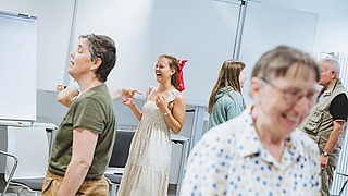 Teilnehmende stehen in einem Workshopraum und kommen miteinander ins Gespräch