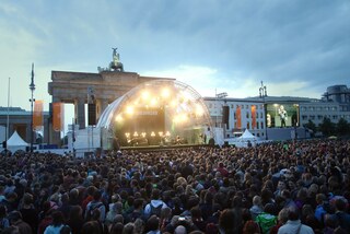 angeleuchtete Bühne vor dem Brandenburger Tor, davor eine große Menge Menschen