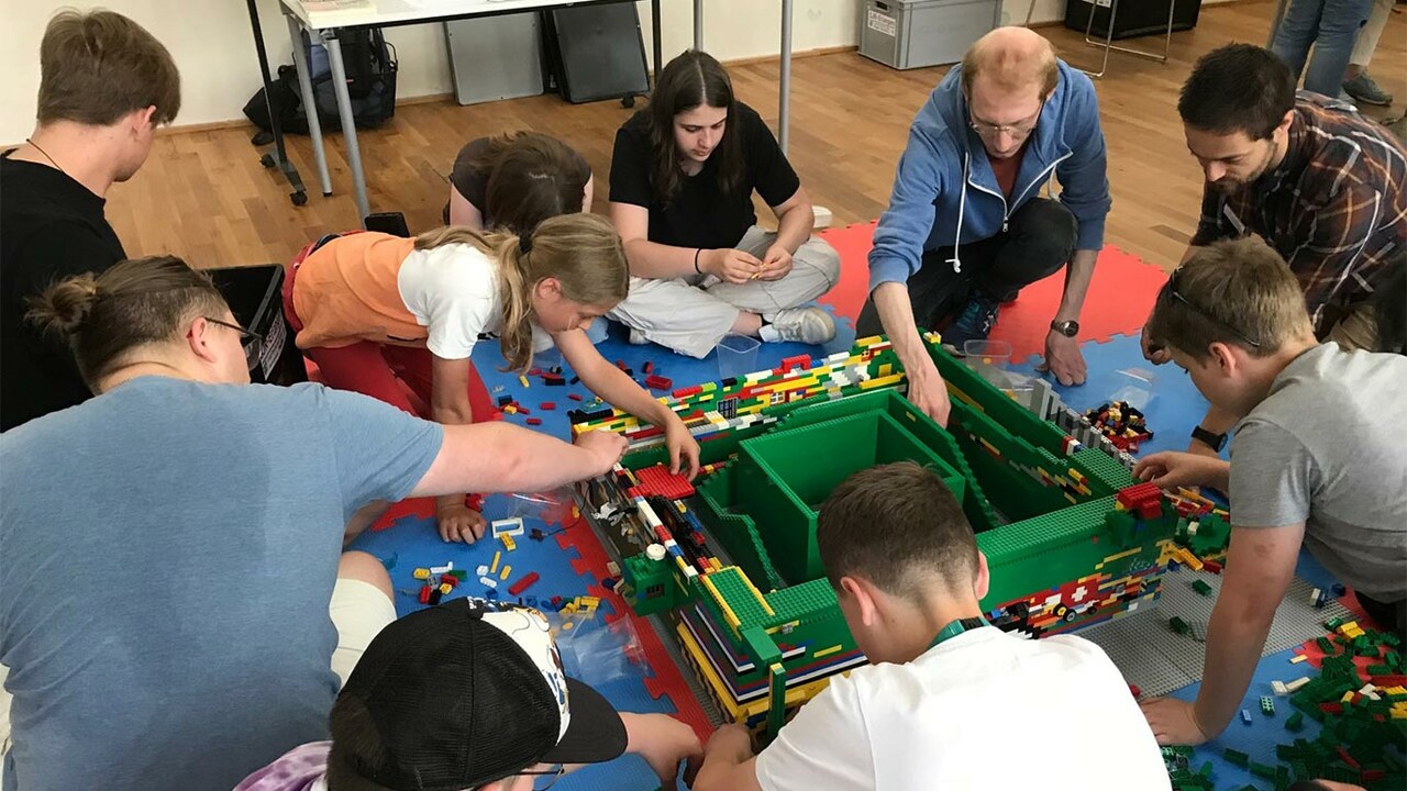Personen verschiedener Altersgruppen, die zusammen Lego bauen 
