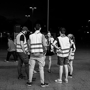 Sechs junge Menschen mit Warnwesten stehen im Kreis und beraten sich.