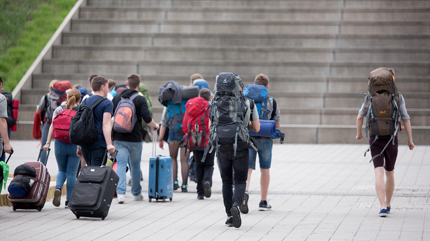 Reisegruppe mit Trollis, Koffern und Rucksäcken