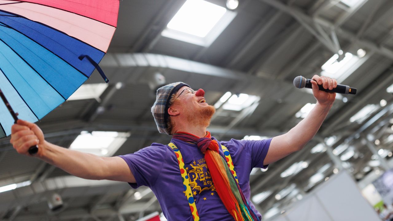 Person mit Mikrofon auf einer Bühne in einer Halle