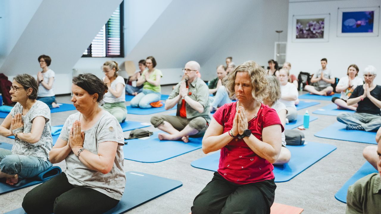 Eine kleine Gruppe junger Frauen kniet auf Yoga-Matten