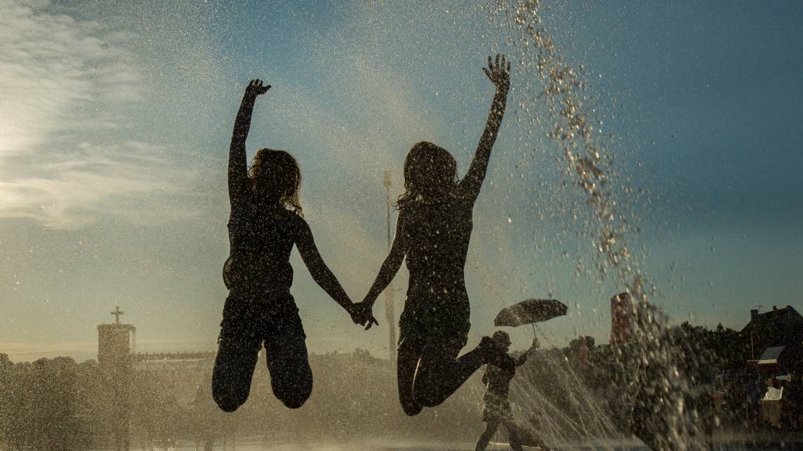 Zwei Mädchen beim Kirchentag in Stuttgart 2015 springen im Wasser und halten sich an den Händen
