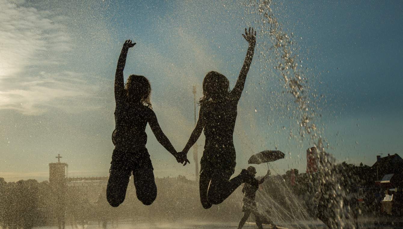 Zwei Mädchen beim Kirchentag in Stuttgart 2015 springen im Wasser und halten sich an den Händen