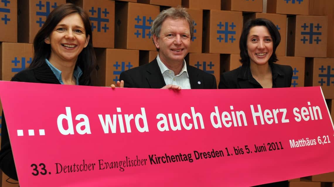 Katrin Göring-Eckardt, Jochen Bohl und Ellen Ueberschär mit einem großen Schild auf dem "da wird auch dein Herz sein" in weiß auf pink steht