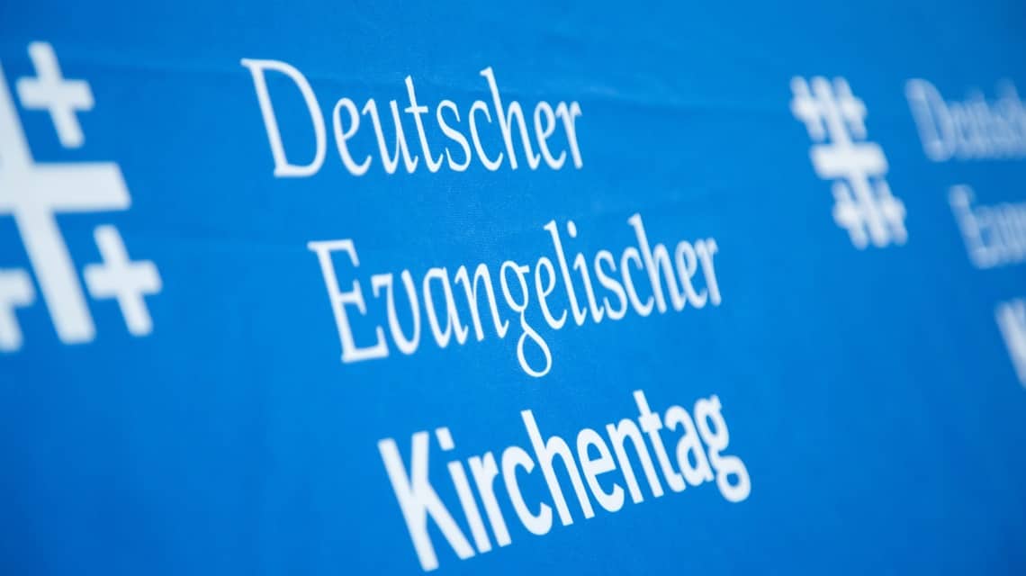Logo des Deutschen Evangelischen Kirchentages mit angeschnittenem Jerusalemkreuz in weiß auf blau