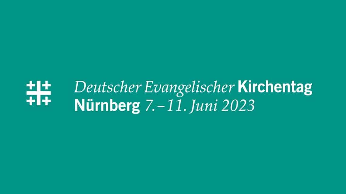 Logo zweizeilig mit Jerusalemkreuz des Kirchentages in Nürnberg 2023 in weiß auf smaragdgrün (mineralblau), der Farbe für Nürnberg