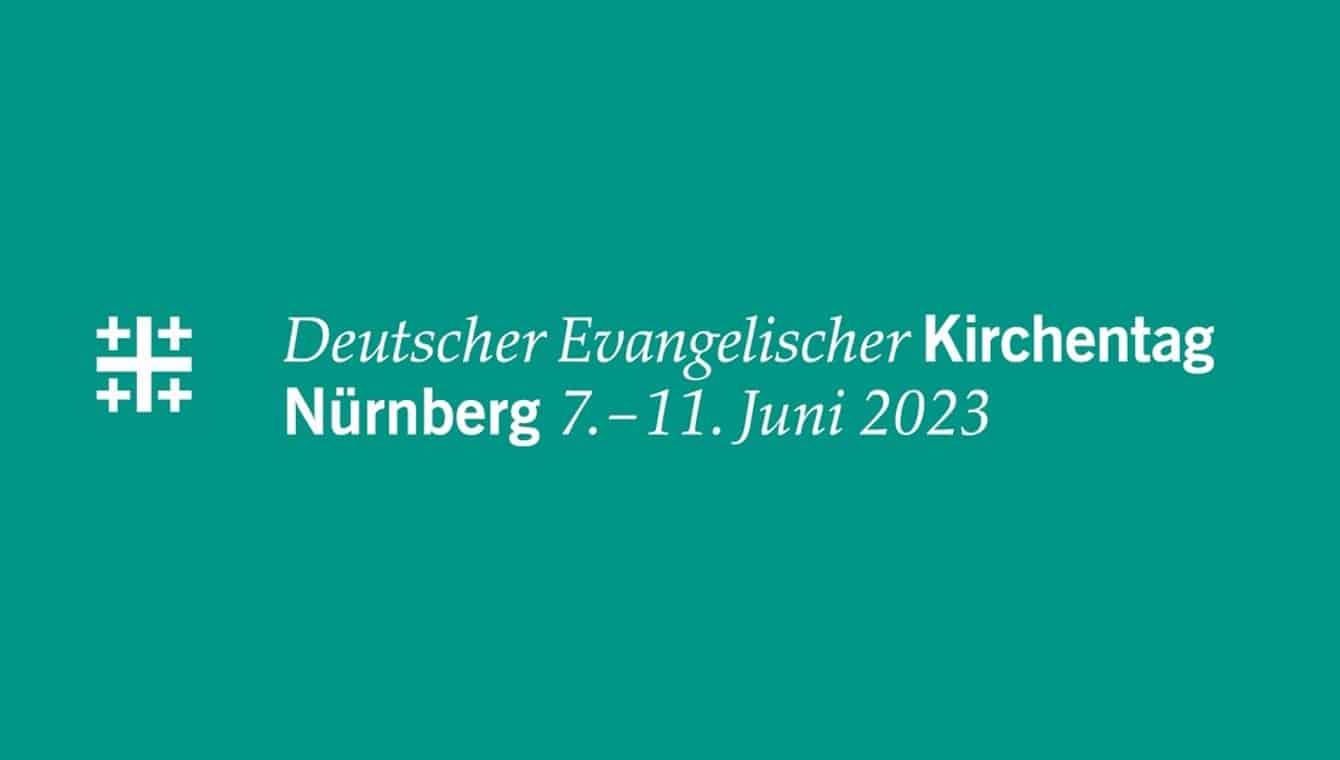 Logo zweizeilig mit Jerusalemkreuz des Kirchentages in Nürnberg 2023 in weiß auf smaragdgrün (mineralblau), der Farbe für Nürnberg