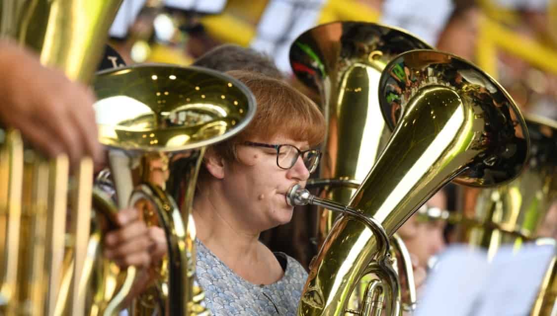 Drei große goldene Tubas, mittig im Bild eine Bläserin mit Brille und rötlichen Haaren, die konzentriert vom Blatt spielt, beim Schlussgottesdienst