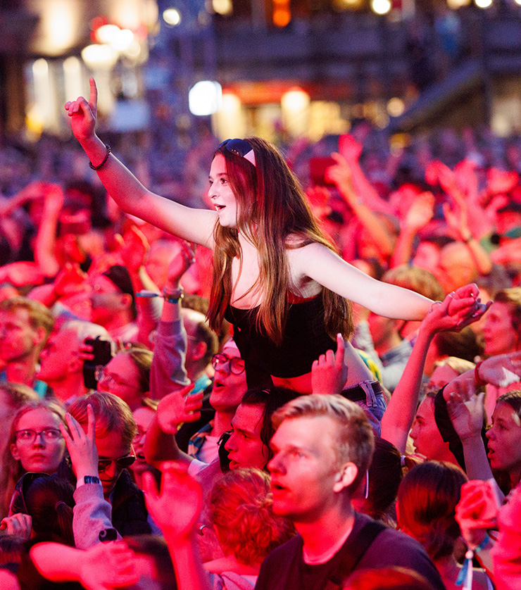 Konzertbesucherinnen beim Konzert von Brings in Nürnberg 2023. Ein Mädchen sitzt über der Menge auf den Schultern und streckt die Arme in den Himmel